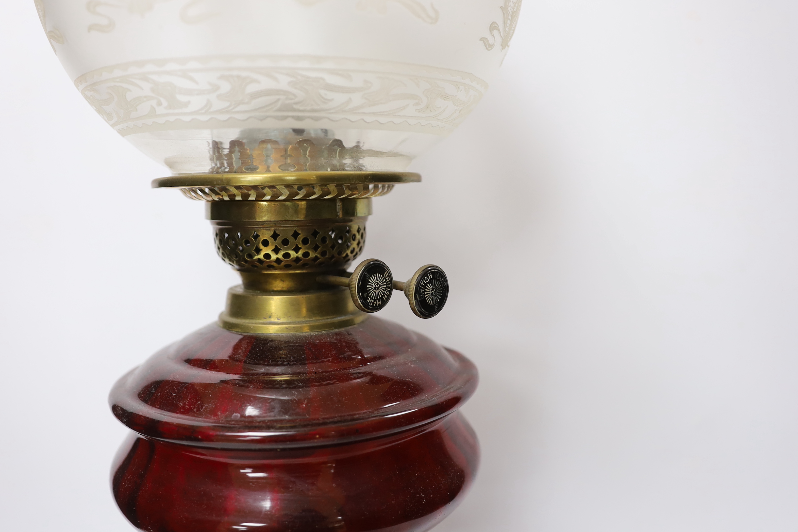 Three oil lamps with glass reservoirs and shades, one with Art Nouveau style base, 62cm high